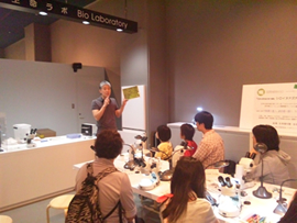 参加者に顕微鏡の使用法と観察対象の説明を行う研究員